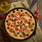 Focaccia, pizza in skillet, italian flat bread with tomatoes, olives and rosemary. Wooden table