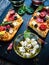 Focaccia - roasted mozzarella sandwiches with salami pepperoni, feta cheese and tomatoes on black stone plate