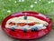 Focaccia stuffed with mozzarella and tomatoes with black olives on a red plate with daisies in the background