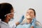 Focus of african american dentist in medical mask and face shield holding dental instruments near cheerful patient