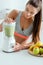 Focus of attractive sportswoman preparing smoothie in blender