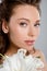 Focus of attractive woman near white blooming flower isolated on grey