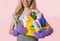 Focus on basket of cleaning supplies. Housewife in apron and purple rubber gloves