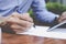 Focus on businessman hand. Businessman writing document in street cafe.