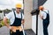 Focus of cheerful repairman standing with hands on hips and smiling near coworker