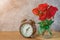Focus of clock black vintage style and Roses in glass jar on sack, wood table. sunlight and cement background