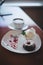 Focus close picture of delightful sweet fancy looking desert chocolate muffin with cherry and cup of coffe on white plate on woode