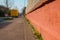 Focus of common dandelion along a brick fence in the foreground. Blurry defocused yellow car in the background. No focus