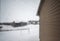 Focus on a dirty residential windo overlooking the side of a house and snow covered area