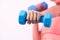 Focus dumbbell hold by blurred vigorous energetic woman doing weight lifting.