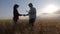 Focus on the ears of wheat. Farmers handshake over the wheat crop in harvest time. Team farmers stand in a wheat field