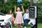 Focus EV station recharging battery for EV car on blurred family. Synchronos