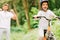 Focus of father cheering son while boy riding bicycle and looking at camera