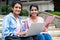 focus on girl with book, Happy College students looking at camera while busy working on laptop on university campus -