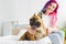 Focus of girl sitting on bed and petting cute bulldog looking away