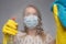 Focus on glass. Cleaning with viruses and bacteria at home. The girl in the mask cleans with a chemical agent in the mask and