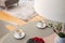 Focus on a gray rug in a living room interior and blurry foreground with coffee cups on a gray dining table