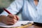 Focus on hand, Close up unrecognizable hands of Young business woman writing down notes at working desk - concept of employee or