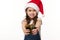 Focus on hands of a blurred lovely little girl in Santa hat, handing a cute Christmas present, isolated white background