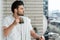 Focus of handsome man with towel on shoulder holding cup of coffee on balcony