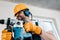 Focus of handyman in helmet and yellow gloves using hammer drill