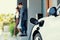 Focus home charging station for EV car, blur progressive family in background.