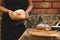 Focus on homemade healthy whole grain sourdough rye bread and ears of wheat, in the hands of female baker in black apron