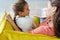 Focus of kid sitting on sofa with happy babysitter holding book