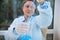 Focus on laboratory pipette in hands of blurred woman scientist, medical biologist pipetting blue liquid into a flask