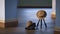 Focus at lady hat hanging on camera tripod, fedora hat on black camera bag with base of blue pillars on wooden floor in vintage