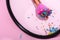 Focus of makeup brush covered in colorful sprinkles reflecting in mirror on pink