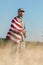 Focus of man in camouflage uniform and cap holding american flag in golden field