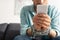 Focus of man with tied hands with chain using smartphone on couch