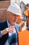 Focus of mature businessman in helmet gesturing while looking at constructor