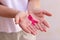 Focus on mature hand holding a pink ribbon  on white