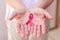 Focus on mature hand holding a pink ribbon  on white