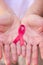 Focus on mature hand holding a pink ribbon  on white