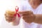 Focus on mature hand holding a pink ribbon  on white