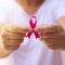 Focus on mature hand holding a pink ribbon  on white