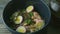 Focus out from noodles dish with mushrooms, boiled eggs, and pitcher with broth