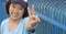 Focus at peace hand sign of overweight Asian woman having funny smiling beside blue fence in public park while exercising to lose