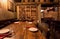 Focus on plates and water glass inside retro restaurant with wooden vintage furniture, wine bottles