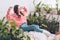 Focus of pretty young woman stretching while sitting in room near lush green plants