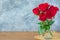 Focus of Red Roses in glass jar on sack, wood table. cement background