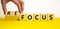 Focus or refocus symbol. Businessman turns wooden cubes and changes the word focus to refocus. Beautiful yellow table white