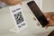 Focus on Scan here to pay text, Close up of hands Scaning QR code for digital contact less payment after shopping -
