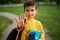 Focus on the schoolboy`s hand gesturing stop. Out of focus adorable schoolboy showing stop with his hand, standing with backpack