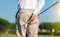 On focus shot of back of a golfer holding a club on a green golf field. The background is out of focus, creating a nice