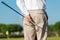 On focus shot of back of a golfer holding a club on a green golf field. The background is out of focus, creating a nice