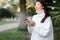 Focus on smartphone in chinese woman hands, girl standing in tropical park.